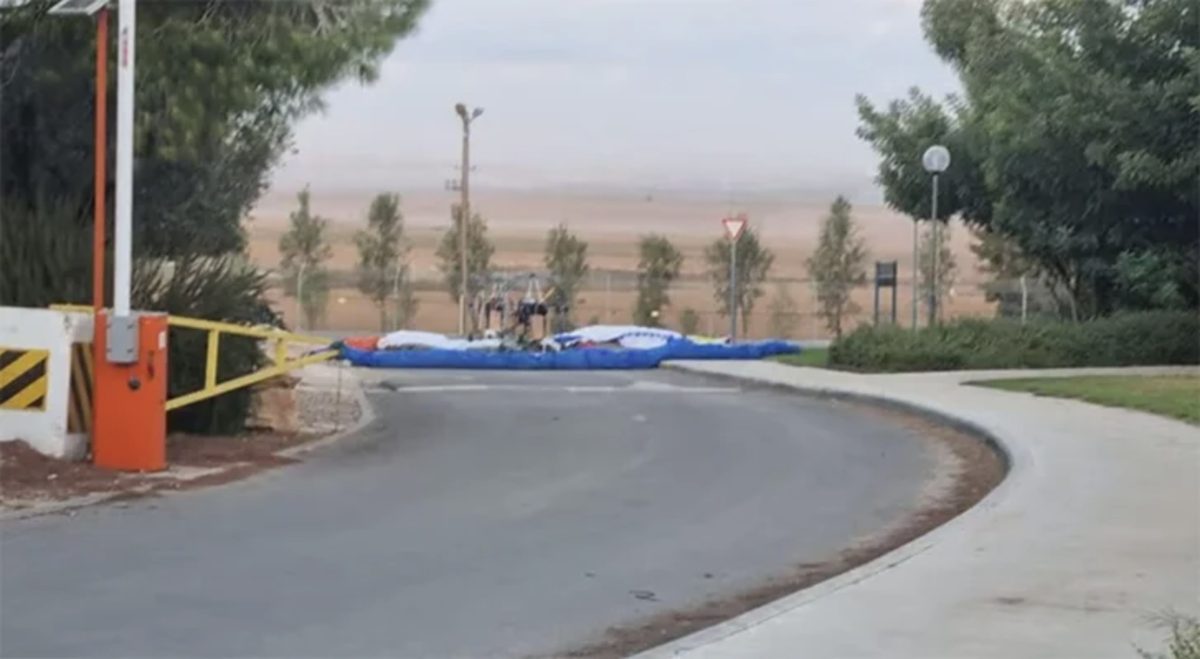 Un parapente motorizado recién aterrizado en la calle de entrada del kibutz, junto a la barrera.