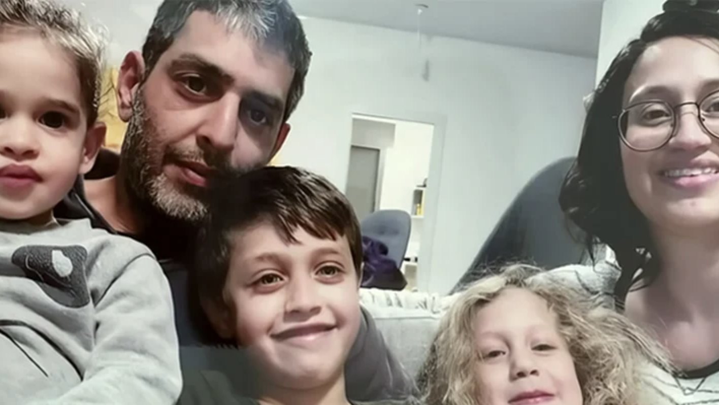 Roy y Smadar Idan con sus tres hijos, sonriendo en el living de su casa.