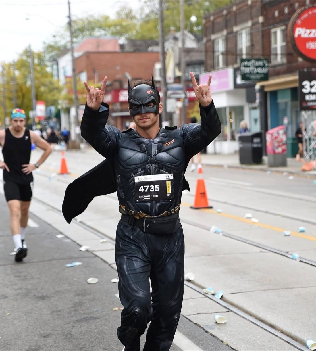 Yoel Levy, disfrazado de Batman, corre una maratón y levanta las dos manos haciendo cuernitos, el gesto de Ariel.